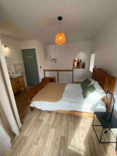 une chambre avec un grand lit et un parquet dans l'établissement Petite maison de village, à Ébreuil