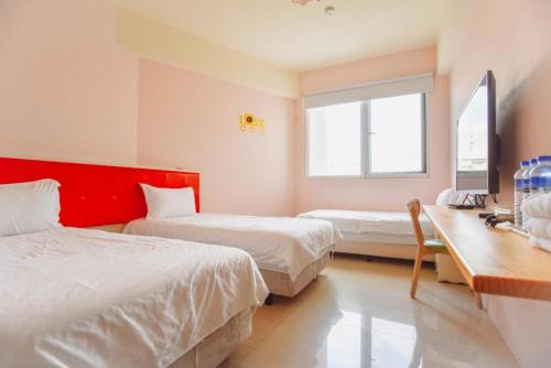 a bedroom with two beds and a desk and a window at King X.S. B&B in Taitung City