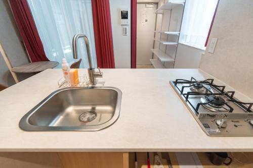 a kitchen counter with a sink and a stove at Apiche Oji in Tokyo