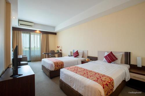 a hotel room with two beds and a flat screen tv at Wiltop by BENCOOLEN in Jambi