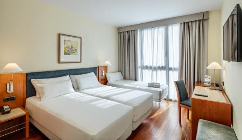 um quarto de hotel com uma grande cama branca e uma secretária em Sercotel Cornellà Barcelona em Cornellà de Llobregat