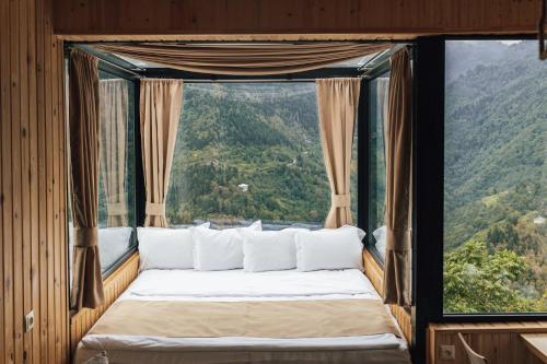 Cama en habitación con ventana grande en Unique Boutique Hotel Near Batumi, en Batumi