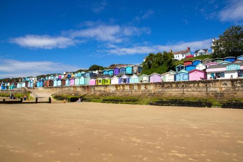 a row of colorful houses next to a beach at Modern 8 Berth Caravan With Decking At Naze Marine Park, Essex Ref 17145P in Walton-on-the-Naze