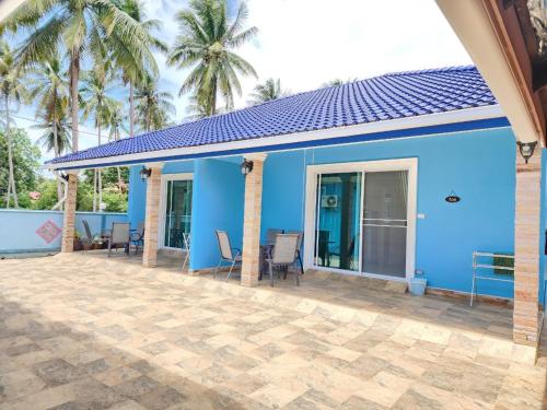 a blue house with chairs and palm trees at Blue Beach Bungalow in Bang Saphan Noi