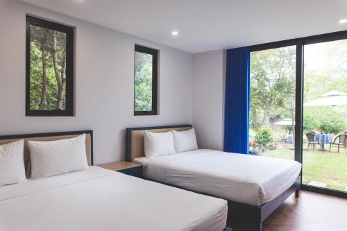 two beds in a room with two windows at Interconnection Ba Vì Venuestay in Hanoi