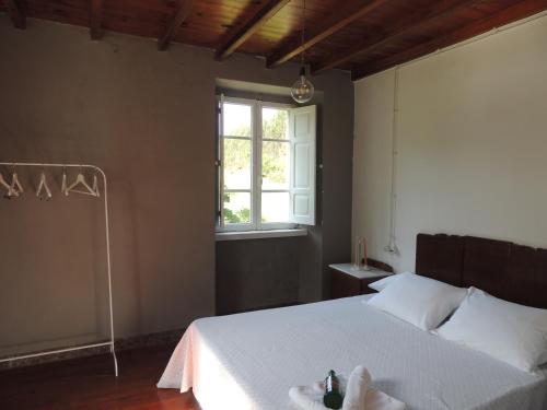um quarto com uma cama branca e uma janela em Casa de Campo Pumarada de Oirín em Foz