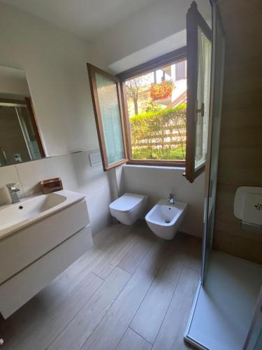 a bathroom with a sink and a toilet and a window at Almida in Castello di Fiemme