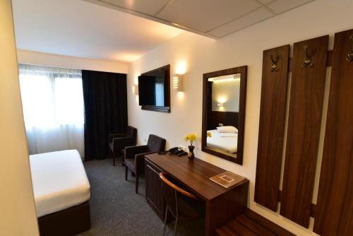 a hotel room with a desk and a bed and a mirror at Hotel Forum in Ploieşti
