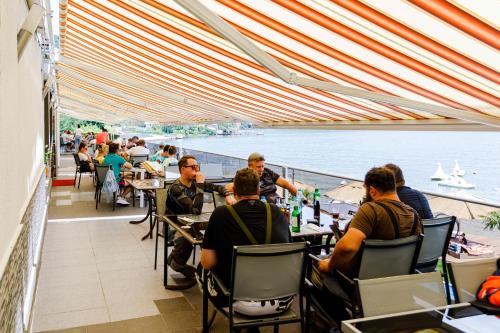 a group of people sitting at tables in a restaurant at Pensiunea Decebal Resort - Cazanele Dunarii in Dubova