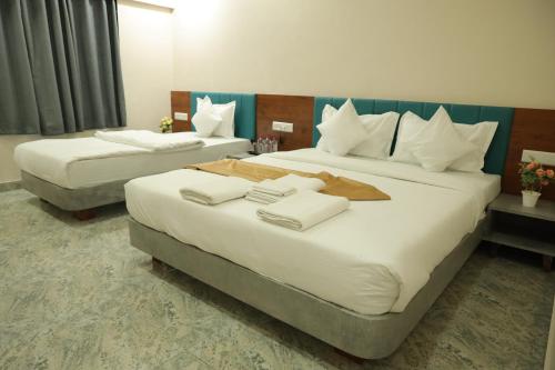 two beds in a hotel room with towels on them at Hotel Lord Krishna in Dwarka