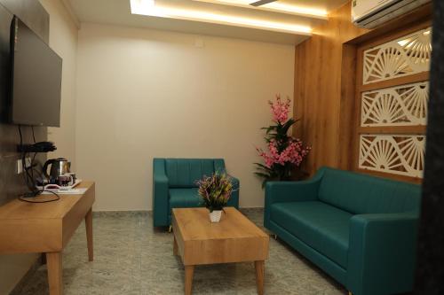 a living room with two blue couches and a table at Hotel Lord Krishna in Dwarka