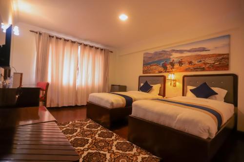 a hotel room with two beds and a painting on the wall at Kathmandu Business Hotel in Kathmandu