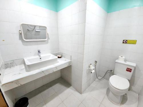 a white bathroom with a toilet and a sink at Blue Beach Bungalow in Bang Saphan Noi