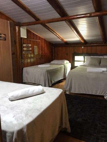 een kamer met drie bedden in een houten kamer bij Sítio do Sol quádruplo wc privativo in Guabiruba