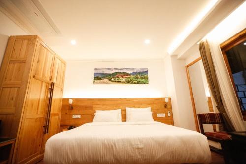 1 dormitorio con 1 cama y una pintura en la pared en Phuntsho Khangsar Hotel, en Thimphu