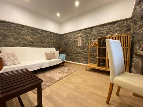 ein Wohnzimmer mit einem Sofa und einem Stuhl in der Unterkunft Penha D'Águia Villa by LovelyStay in Porto da Cruz