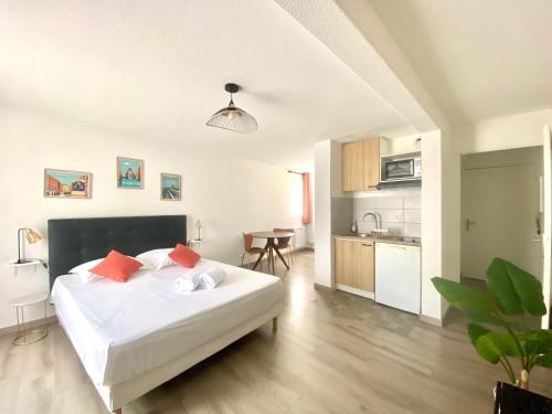 une chambre avec un grand lit blanc et une cuisine dans l'établissement Le Chaleureux - Studio proche du Jardin Compans, à Toulouse