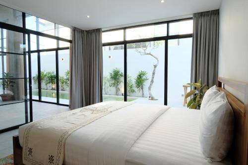 - une chambre avec un grand lit et de grandes fenêtres dans l'établissement Manresa Villa Bali 3, à Canggu