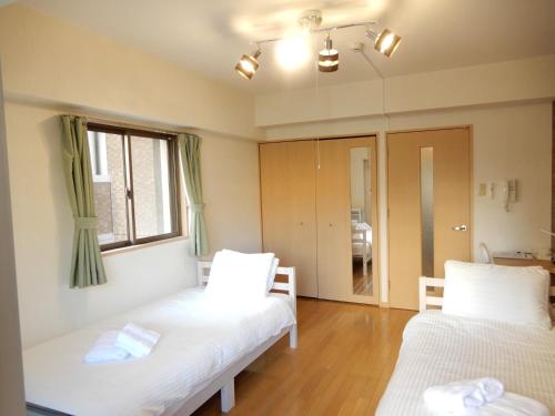 ein Zimmer mit zwei Betten und einem Fenster in der Unterkunft ピオーレ大手門501 in Susakiuramachi