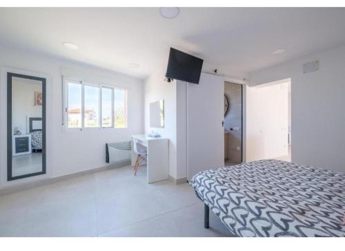 een witte slaapkamer met een bed en een bureau. bij costa sur in Vinarós