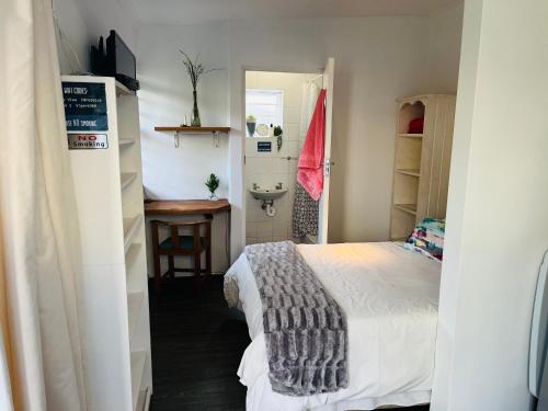 a small bedroom with a bed and a sink at Settlers Valley Cottage in Port Elizabeth
