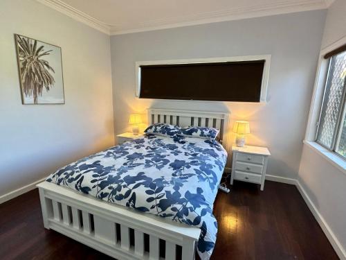 a bedroom with a bed with a blue and white comforter at Jacaranda Cottage in Broadwater