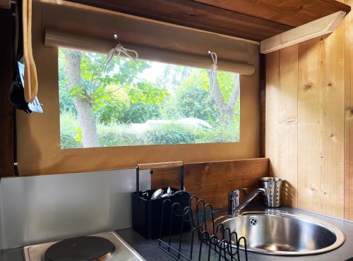 a kitchen with a sink and a window at Camping Canal de Berry in Saint-Amand-Montrond