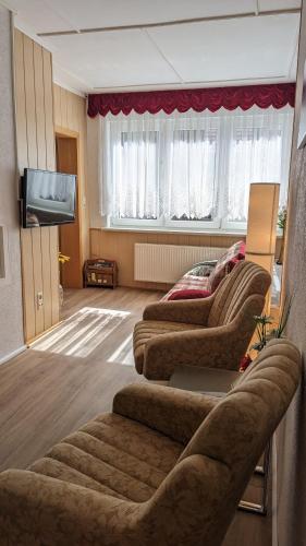 a living room with three couches and a flat screen tv at Gästehaus Fehrenbacher Schweiz in Masserberg