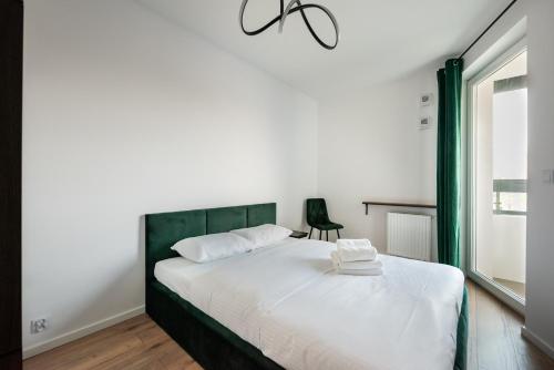 una camera con letto bianco e testiera verde di Nova Sfera Green Apartment a Varsavia