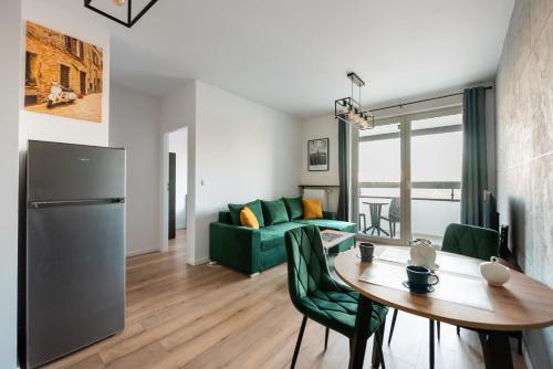 a living room with a table and a green couch at Nova Sfera Green Apartment in Warsaw