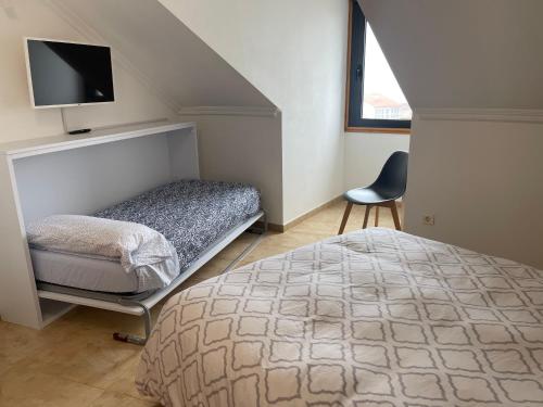 - une chambre avec un lit, une télévision et une chaise dans l'établissement Brisas del mar, à L'île d'Arousa