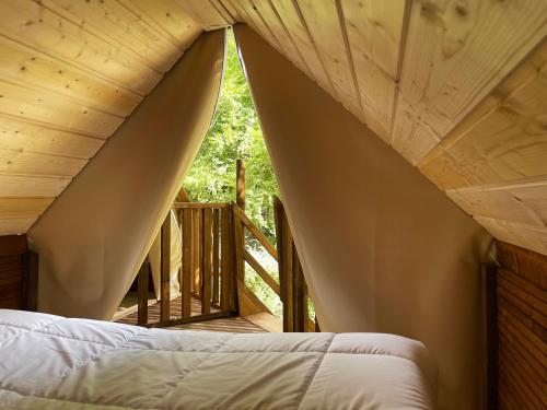 Cama en habitación con techo de madera en Camping Canal de Berry, en Saint-Amand-Mont-Rond