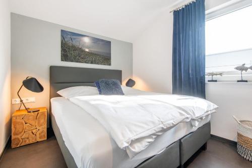 een slaapkamer met een bed met witte lakens en een raam bij Tondernerstrasse 10 Haus Sauerland in Westerland