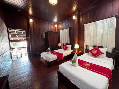 two beds in a room with wooden walls at Villa Vieng Sa Vanh Hotel in Luang Prabang