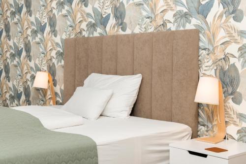 a bedroom with a bed with a tropical wallpaper at Dagály Apartments by UrbanRent in Budapest