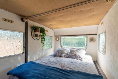 a bed in the side of a trailer with two windows at Cocoon insolite in Pernes-les-Fontaines