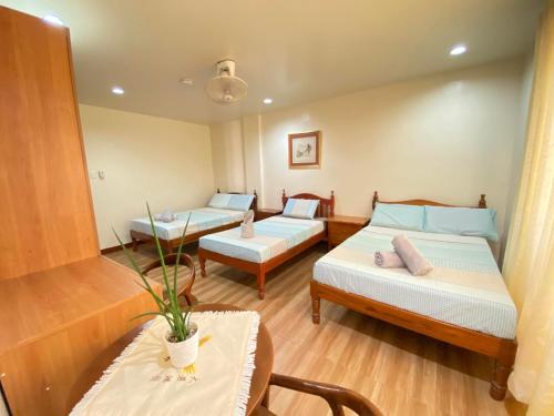 um quarto de hotel com duas camas e uma mesa em Tessie's Home Stay Bed & Breakfast em Puerto Princesa