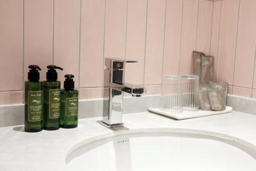 a bathroom sink with two green bottles on it at The Quarter Ratchathewi by UHG in Bangkok