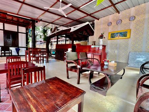 um restaurante com mesas e cadeiras de madeira e uma mesa em Villa Vieng Sa Vanh Hotel em Luang Prabang