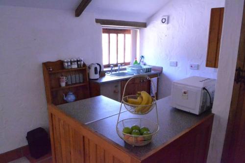 a kitchen with a basket of fruit on a counter at Cozy, open plan barn with log burner in Truro