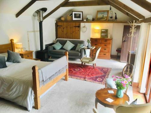 a bedroom with a bed and a living room at Cozy, open plan barn with log burner in Truro