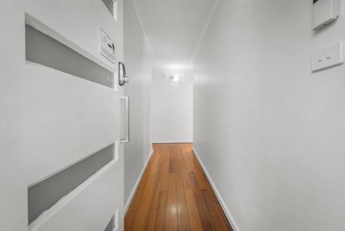 a hallway with white walls and a wooden floor at Large house close to the city tranquil setting in Hobart