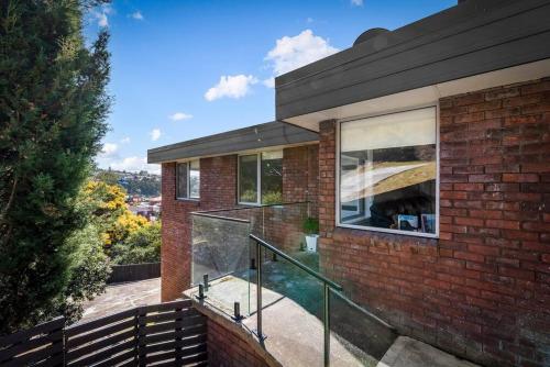 a brick house with a glass railing on a balcony at Large house close to the city tranquil setting in Hobart