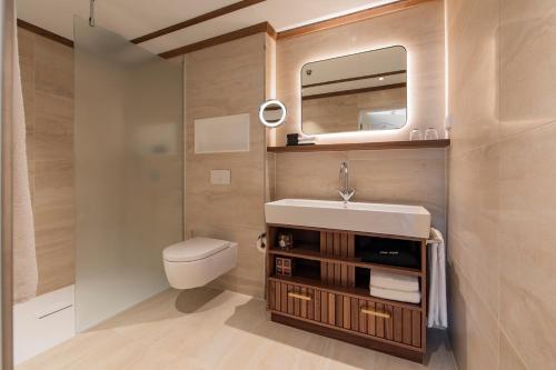 ein Badezimmer mit einem WC, einem Waschbecken und einem Spiegel in der Unterkunft The Historic Huis ter Duin in Noordwijk aan Zee