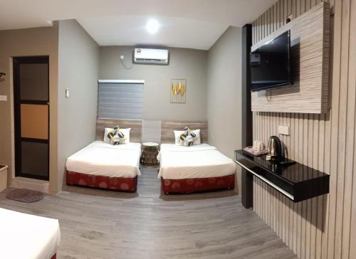 a hotel room with two beds and a flat screen tv at Tc theme park Guest house in Kuantan