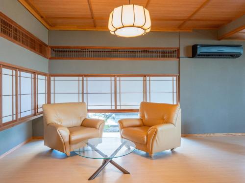 two chairs and a glass table in a room with windows at 18歳以上の宿 澄江知多 in Utsumi