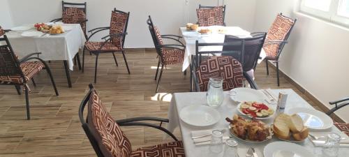 a dining room with tables and chairs with food on them at Apartmani Hani in Trebinje
