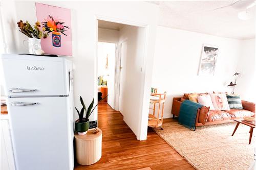 ein Wohnzimmer mit einem Kühlschrank und einem Sofa in der Unterkunft Le Mardi Gras! Holiday Apartment on Wallis Lake, Forster NSW in Forster