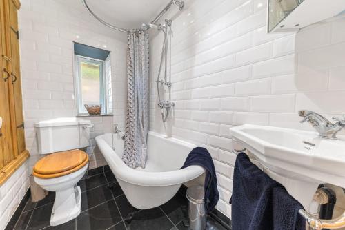 y baño con aseo, bañera y lavamanos. en Sun Cottage with stunning lake views, Coniston en Coniston