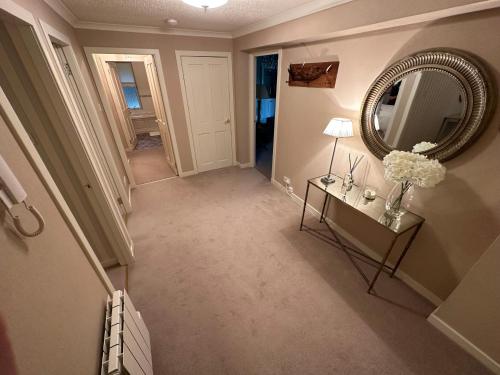 a hallway with a mirror and a table with flowers at One Dunbar Court Gleneagles Village in Auchterarder